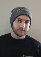 male wearing dark Grey beanie with hour glass logo with Take Root Movement next to it