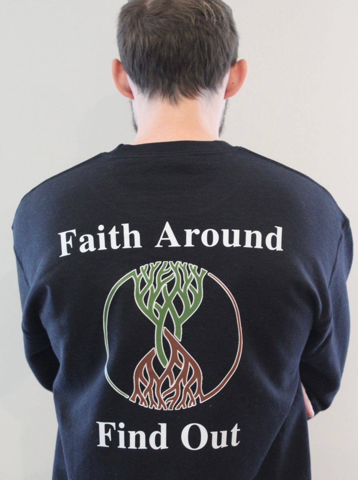Black Take Root Movement sweatshirt with ‘Faith Around Find Out’ text and intertwined tree-and-roots logo on the back.