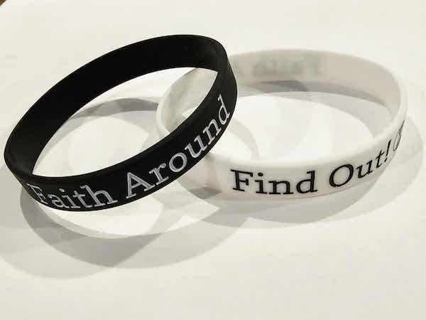 Black and white Take Root Movement silicone bracelets with the ‘Faith Around Find Out’ faith based message and circular tree and roots logo displayed on a clean surface.